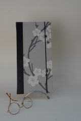 <h5>Carnet de Poète</h5><p>Carnet cousu, cuir noir et papier décor fleurs du japon. élastique de fermeture et petite déco boutons fleurs coordonné à l'ensemble.</p>